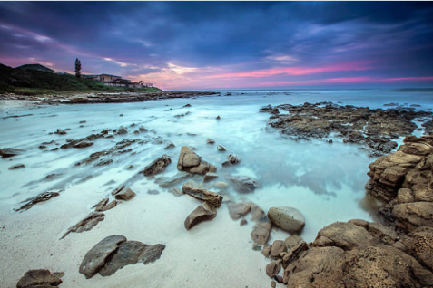 Haga Beach rocky shoreline and turquoise water beneath a pink evening sky